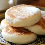Pain batbout marocain fait maison, moelleux et doré, empilé sur une assiette décorative, prêt à être dégusté.